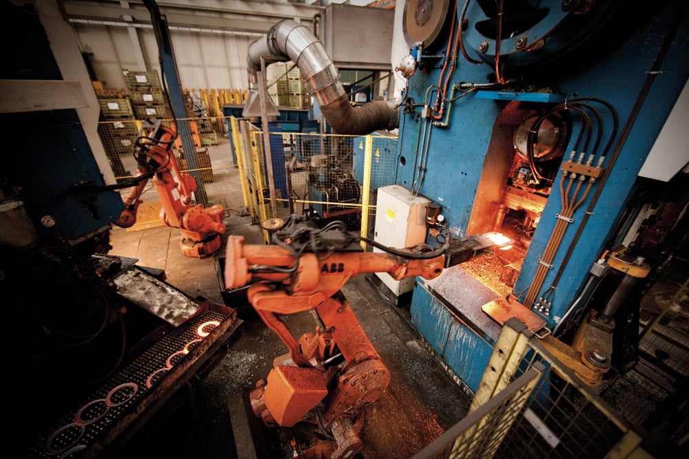 Foto moderna di officina produttiva con macchine operative e personale al lavoro – rappresentazione di un’azienda globale e tecnologicamente avanzata.
