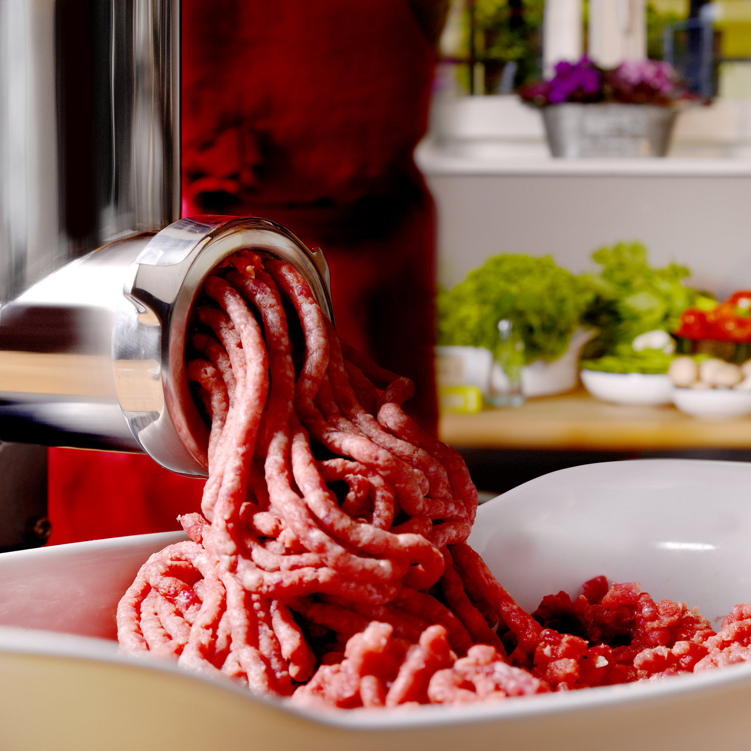 Foto di un tritacarne in funzione con carne macinata che fuoriesce